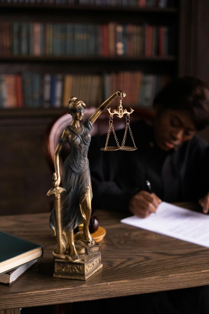 pexels-photo-6077476-6077476 Close-up of Lady Justice figurine on a lawyer's desk with books and documents.